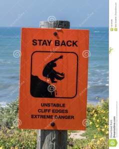 unstable-cliffs-warning-sign-unstable-cliffs-warning-sign-wooden-post-over-cliff-near-ocean-side-102184286